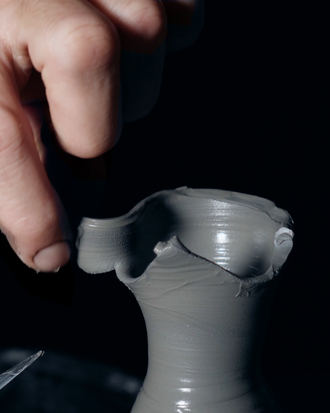 A working hand pressing the hand-formed rim of a wet Valdaire vessel