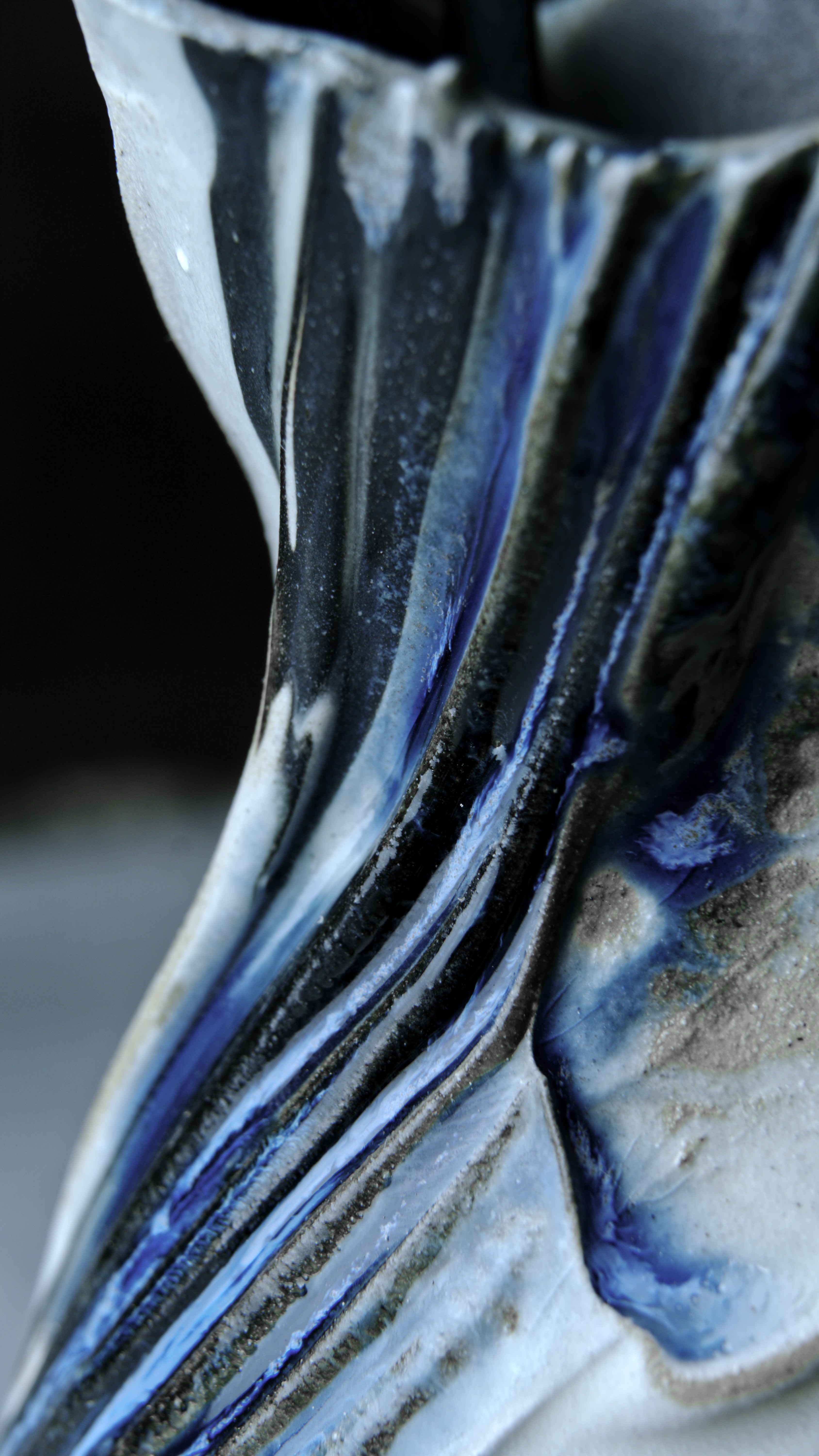 Macro detail of a Valdaire vessel — throwing ridges and blue-grey glaze breaking to bare clay
